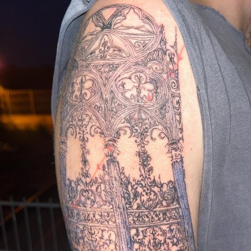 Oberarm-Tattoo: gotisches Maßwerk mit Spitzbögen, Fensterrosen und ornamentalen Säulen, feine schwarze Linien