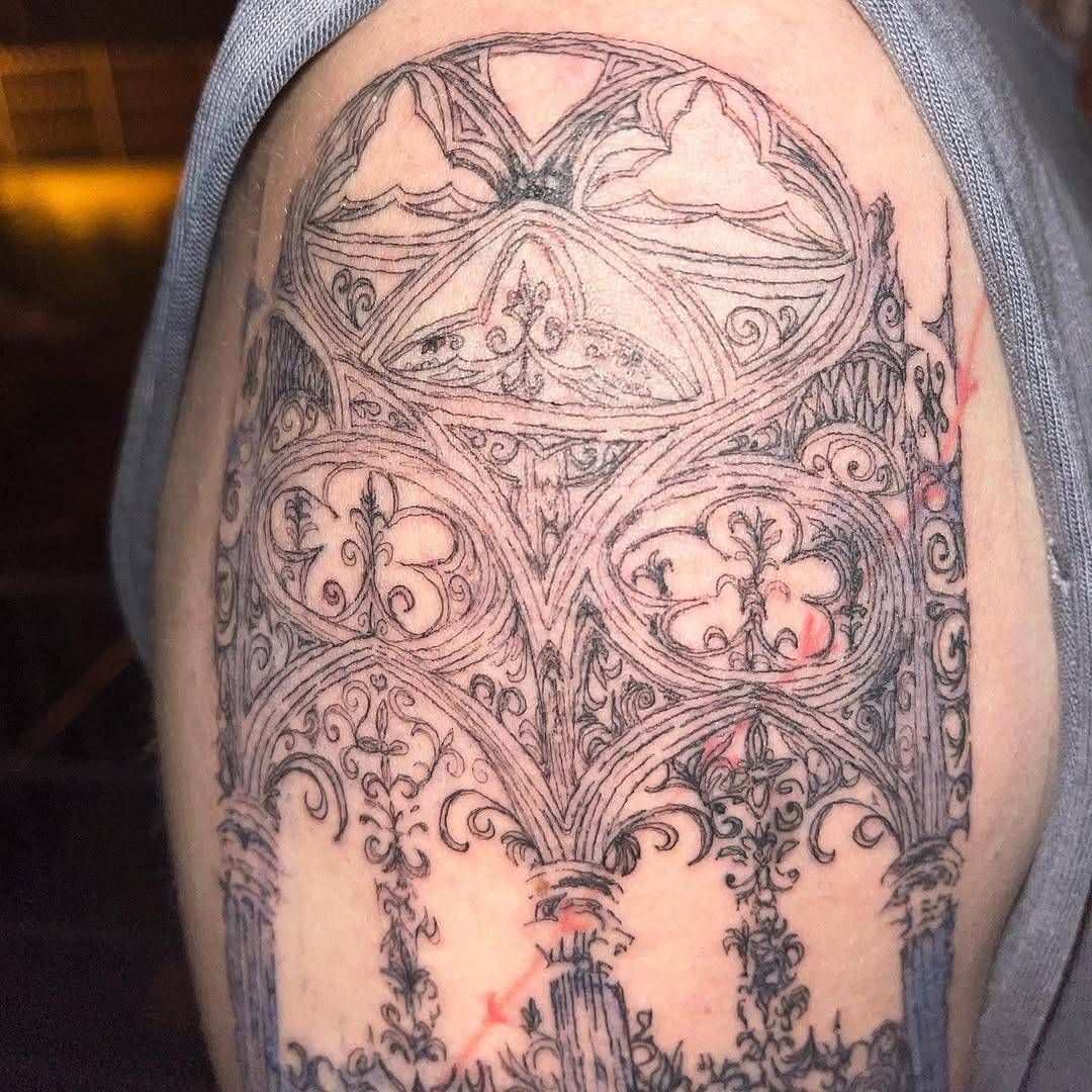 Oberarm-Tattoo: gotisches Maßwerk mit Spitzbögen, Fensterrosen und ornamentalen Säulen, feine schwarze Linien